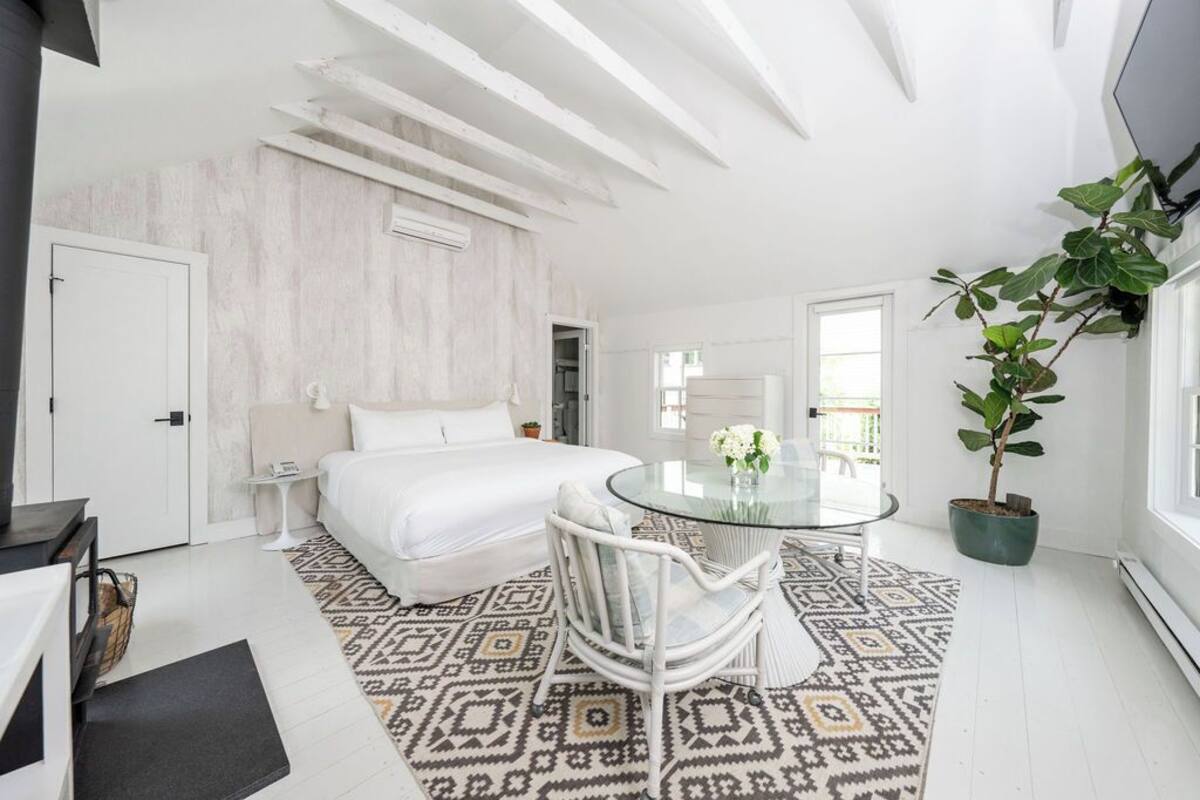 Un dormitorio moderno con cama, mesita de noche y una mesa de vidrio con sillas.