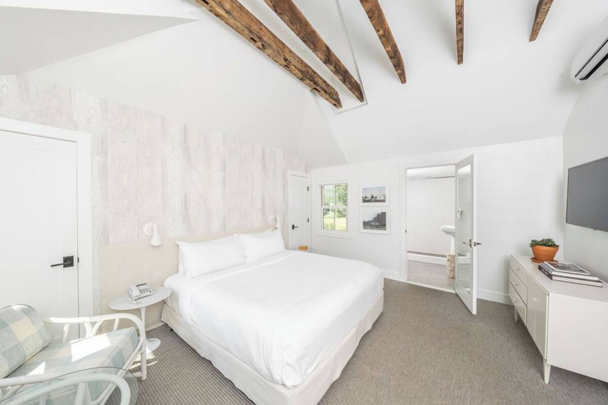 Un dormitorio moderno con una cama grande, una mesita, una silla y un escritorio.