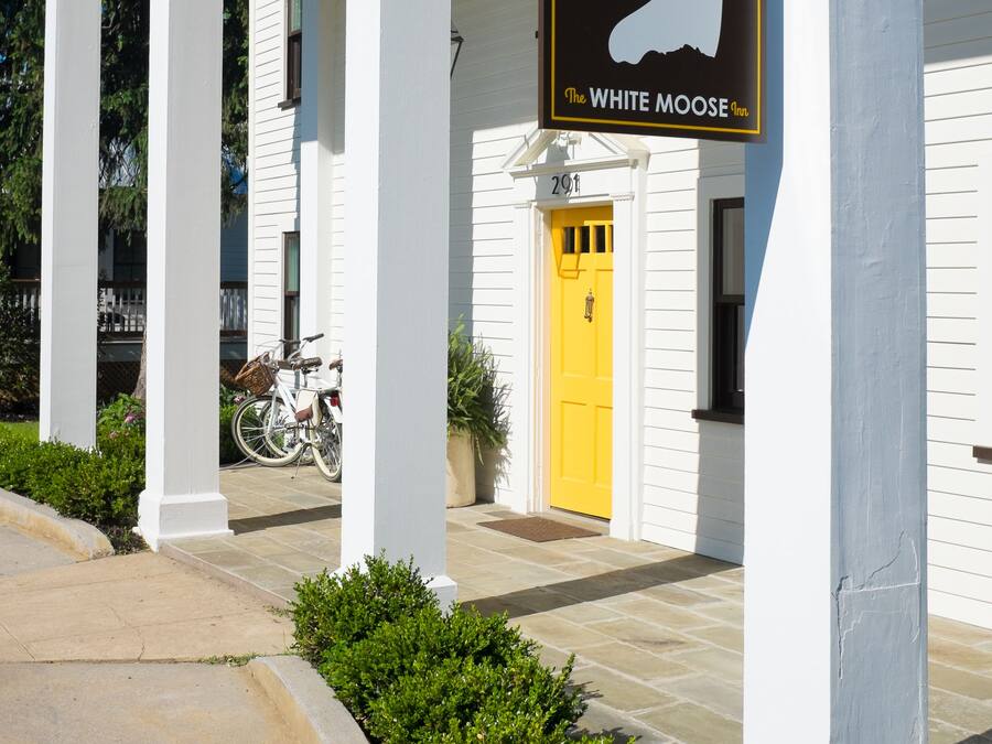 A building with a yellow door and a sign that reads "The White Moose Inn."