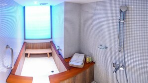 A modern bathroom with a wooden bathtub, a shower area, and a small seating bench. - Energy Inn (Taipei)