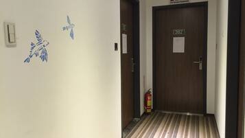 A hallway with a striped floor, two doors labeled 3B1 and 3B2, and a fire extinguisher mounted on the wall.