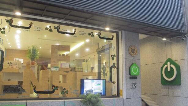 A hotel entrance with a dragon decoration on the wall, a staircase, and a green power button sign. - Energy Inn (Taipei)