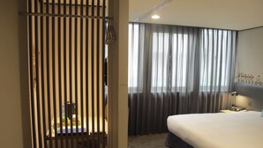 A hotel room with a bed, a desk, a chair, and a window with curtains. - Energy Inn (Taipei)