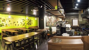 A restaurant with green walls, wooden tables, and black chairs. There is a kitchen area with stainless steel appliances and a sign indicating it's staff only. - Energy Inn (Taipei)