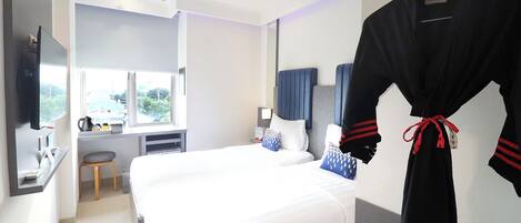 Habitación de hotel con una cama grande, un escritorio, una silla, una bata colgada en la pared y una ventana con vistas.