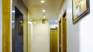 Un pasillo con alfombra roja, puertas de madera y un cuadro enmarcado en la pared.