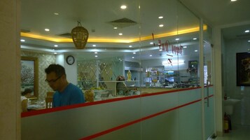 A restaurant with a glass partition, a clock on the wall, and a hanging light fixture.