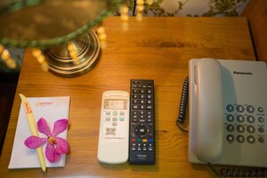 Una mesa de madera con un teléfono Panasonic, un control remoto Toshiba y un folleto con diseño floral.