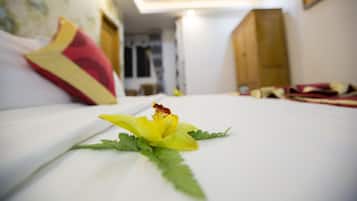A hotel room with a bed, a flower on the bed, and a view of the hallway.