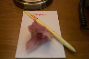 A hotel name card with a pen and a flower on it.