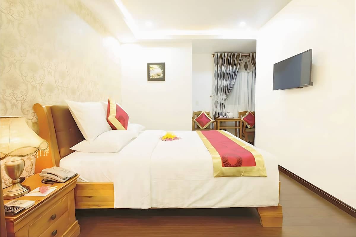 A neatly arranged hotel room with a bed, bedside table, lamp, and a television mounted on the wall.