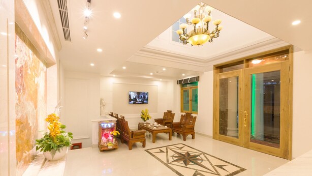 A well-lit lobby with a chandelier, a dining area with wooden chairs, a TV on the wall, and a large window with green lighting. - The Airport Hotel (Ho Chi Minh City)