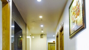 A hotel hallway with a red carpet, wooden doors, and a framed picture on the wall. - The Airport Hotel (Ho Chi Minh City)