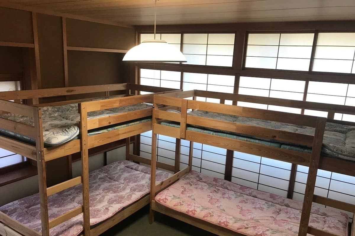 Bunk beds with floral bedding, wooden walls, and a hanging light fixture.