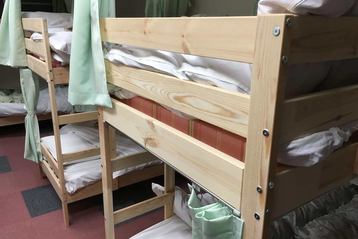 A bunk bed with a wooden frame, a lower shelf, and a pull-out drawer.