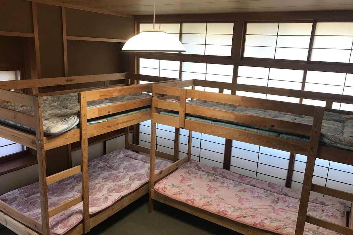 A room with bunk beds, a hanging light fixture, and a window with a grid pattern.