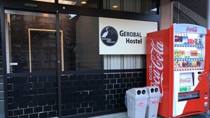 Indgang til et hostel med en Coca-Cola automat og skraldespande.