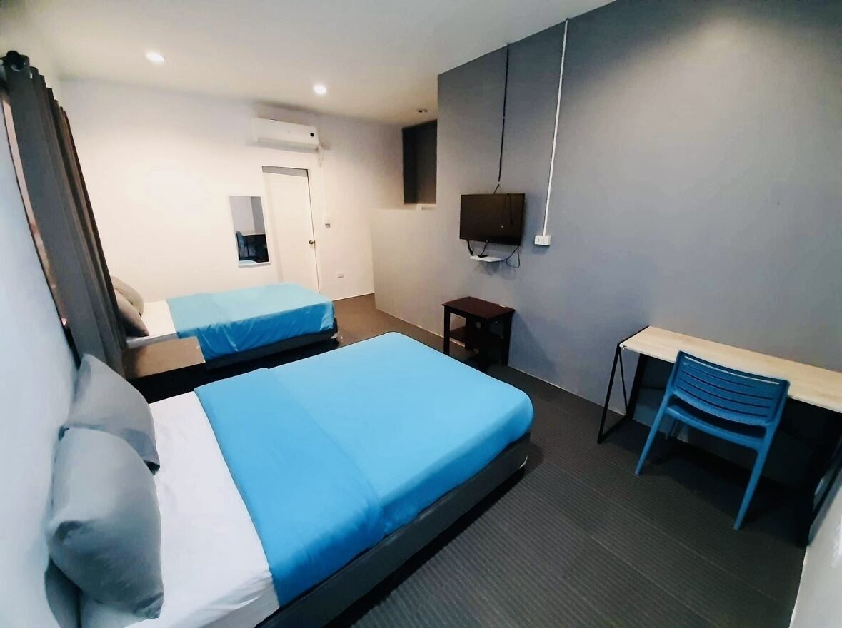Una habitación de hotel con dos camas, un escritorio, una silla, un televisor y una puerta.