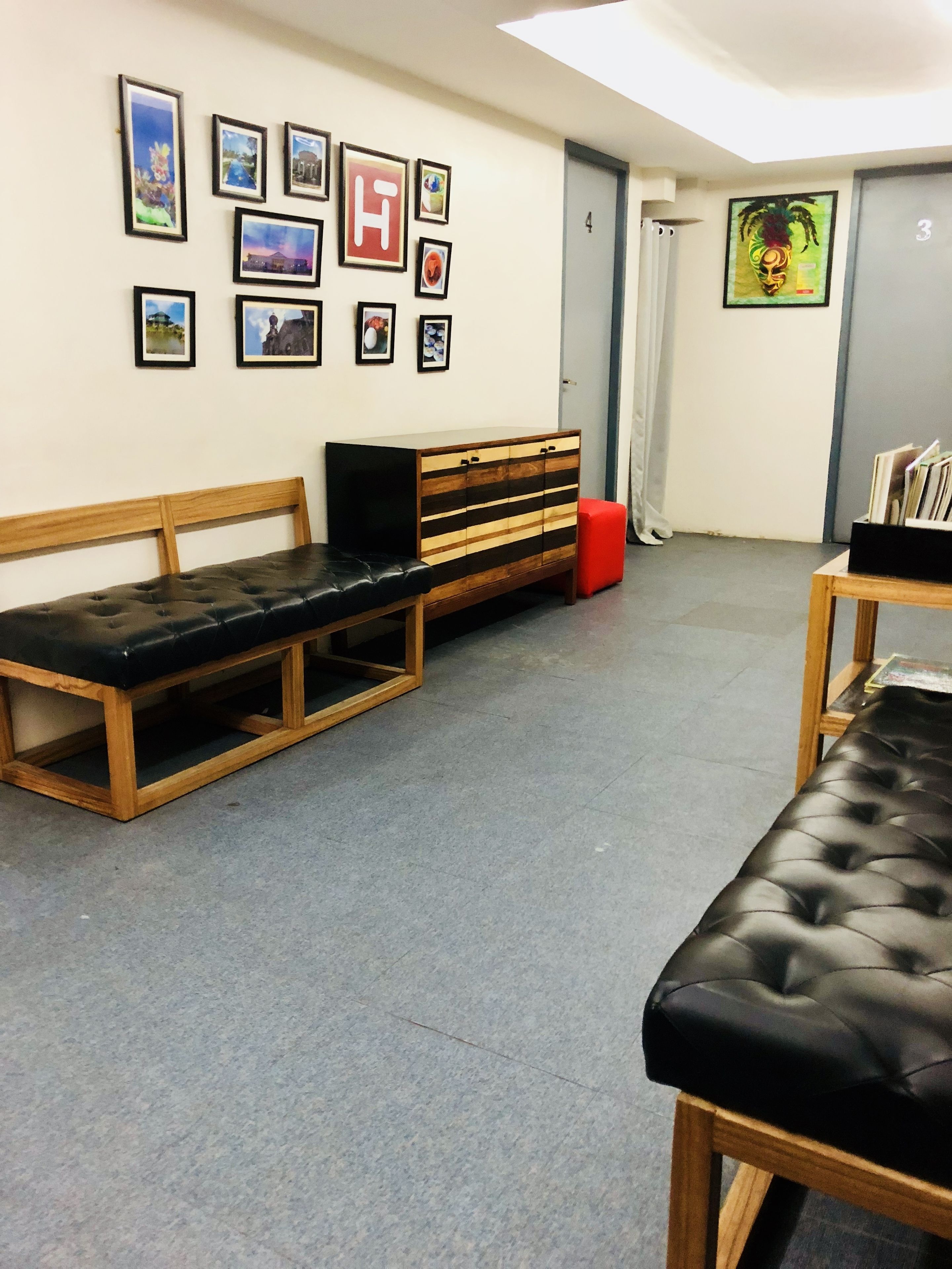 Una habitación con un banco de madera, un reposapiés rojo y una mesa de madera con un asiento acolchado negro.
