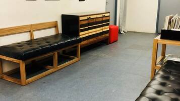 Una habitación con un banco de madera, un reposapiés rojo y una mesa de madera con un asiento acolchado negro.