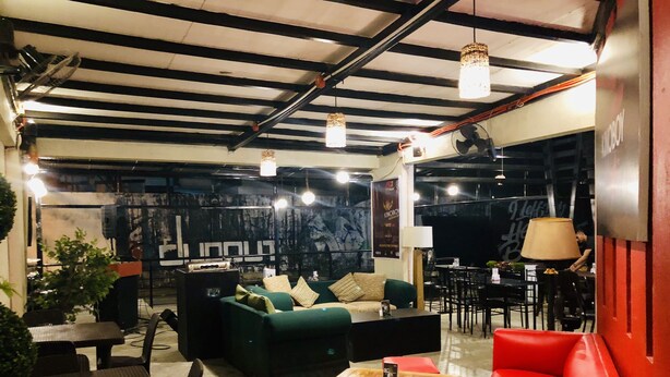 Un área de estar moderna con un sofá, sillas rojas, una mesa de centro de madera y una mesa de comedor con sillas.
