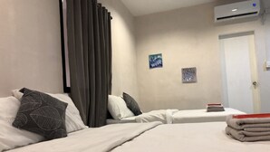 Una habitación de hotel con dos camas, una ventana con cortinas, aire acondicionado y una puerta.