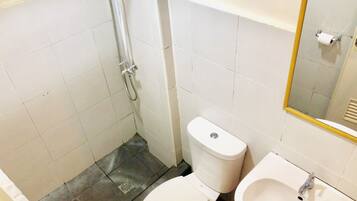Un baño pequeño con inodoro, lavamanos y ducha.