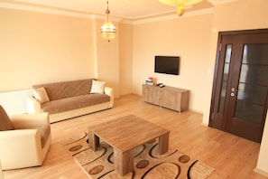 A living room with a sofa, a coffee table, and a television mounted on the wall.