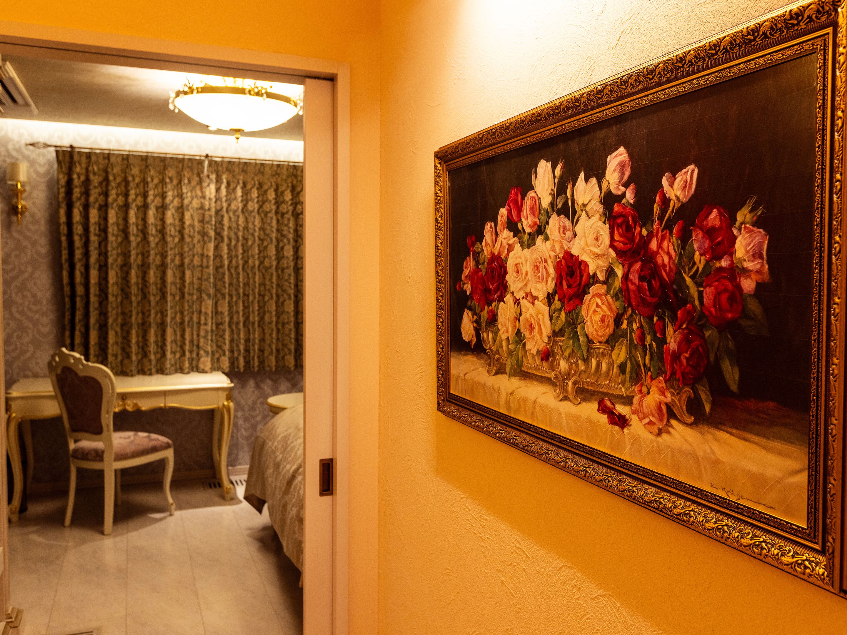 Una habitación con una mesa de comedor y sillas, un cuadro de flores en la pared y una araña.