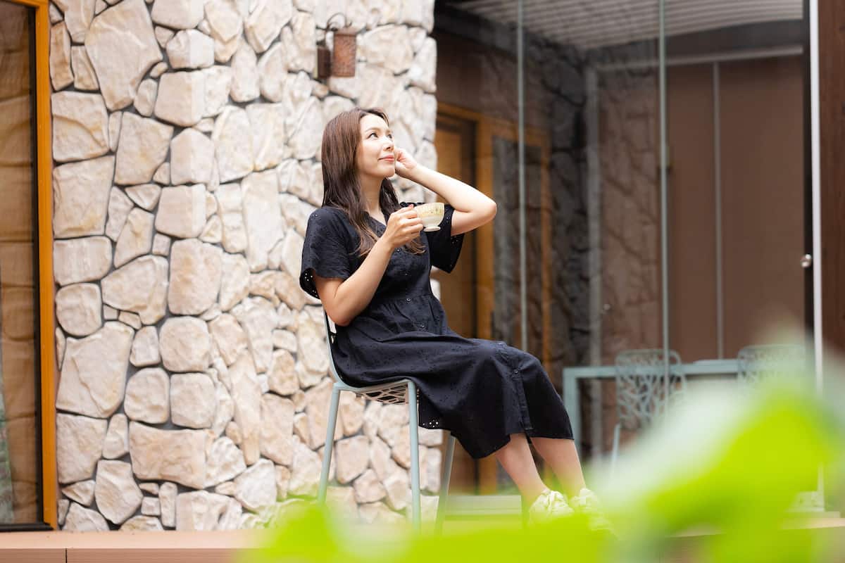 A person sitting on a chair outside a building with a stone wall.