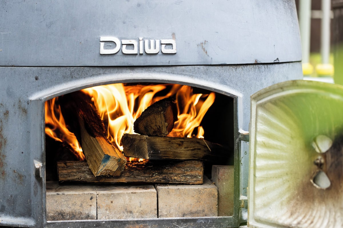 A wood-fired oven with visible flames burning logs inside.
