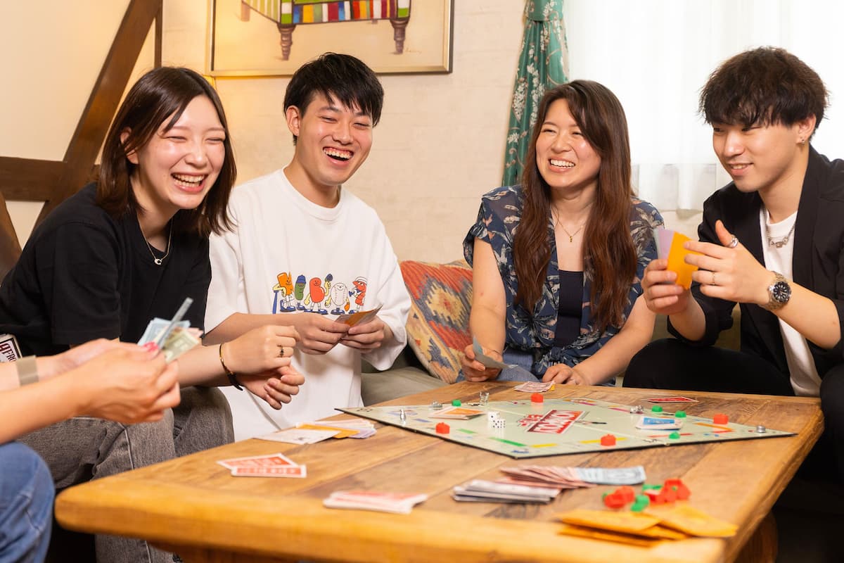 A group of people playing a board game at a wooden table.
