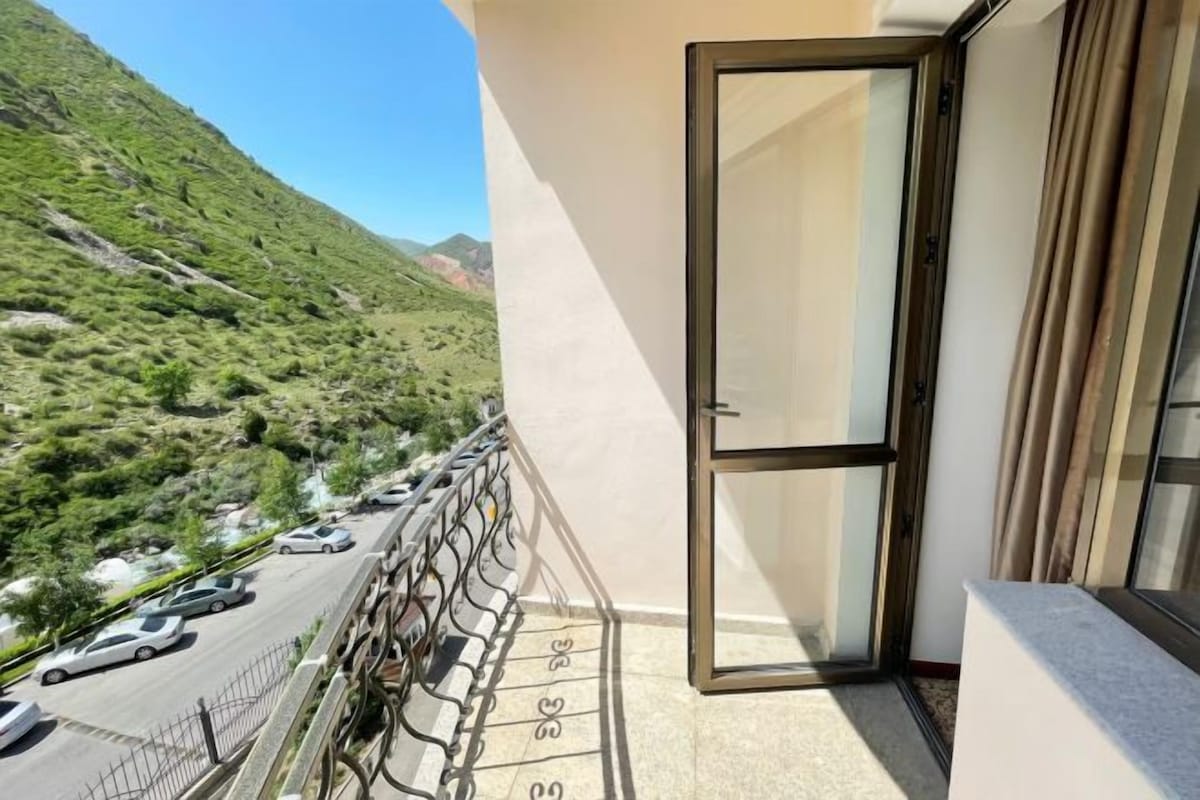 A balcony with a view of a road and green hills.