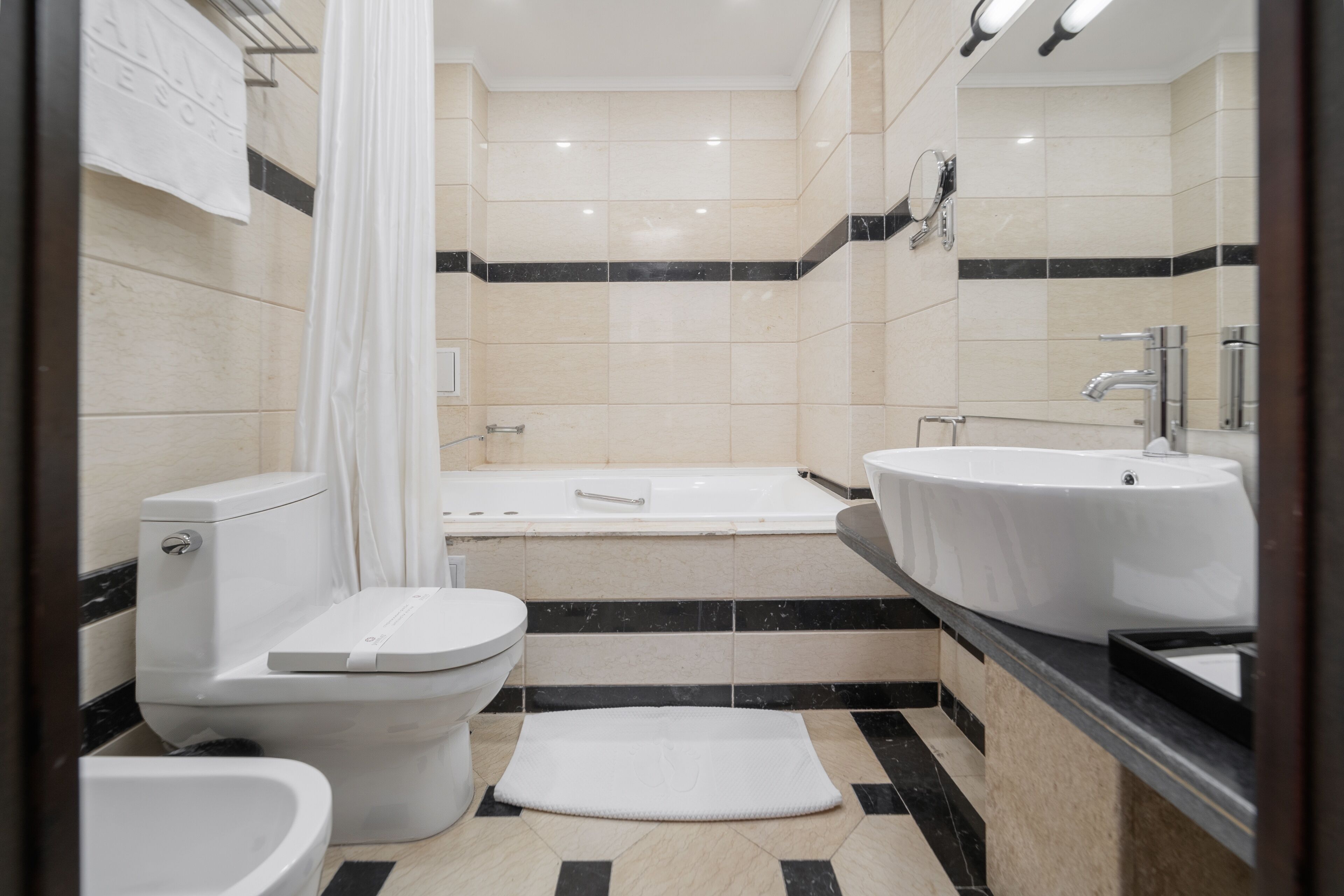 Uma casa de banho moderna com sanita, bidé, banheira e duas pias.