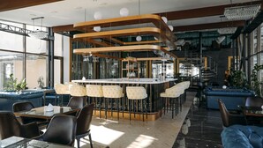 A modern bar area with a curved wooden structure, bar stools, and a seating area with sofas and tables. - Jannat Resort (Koy-Tash)