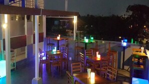 An outdoor dining area with tables and chairs, illuminated by colored lights. - Asian Smile Hotel (Yangon)