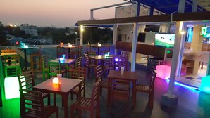An outdoor restaurant with wooden tables and chairs, illuminated by ambient lighting. - Asian Smile Hotel (Yangon)
