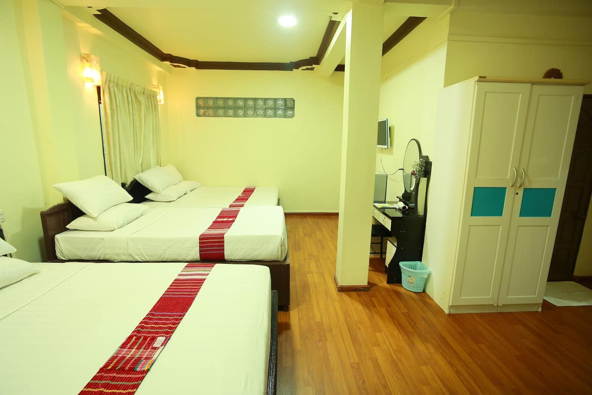 A hotel room with two beds, wooden flooring, a wardrobe, and a desk with a mirror.