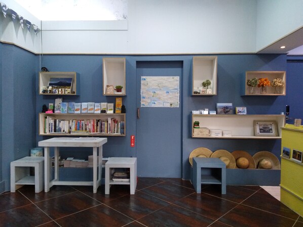 Een kamer met een blauwe muur, houten planken, een kaart en een klein tafeltje met krukjes.