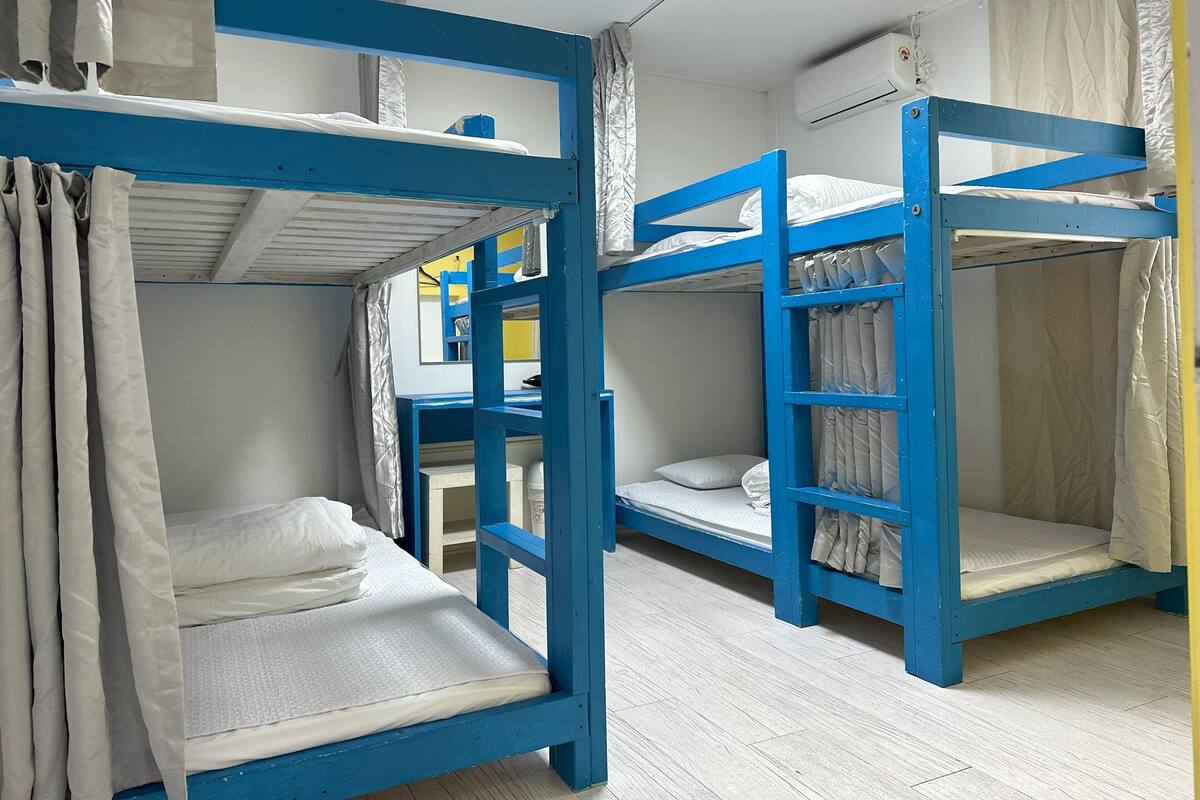 Une chambre de dortoir équipée de lits superposés, d’un bureau et d’un appareil de climatisation.