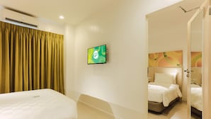 Ein Hotelzimmer mit einem Bett, einem an der Wand befestigten Fernseher und einer Tür zu einem weiteren Raum.