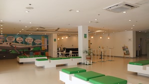 Eine geräumige Lobby mit grünen Sitzbereichen, einem Empfangstresen und Wandgemälden.