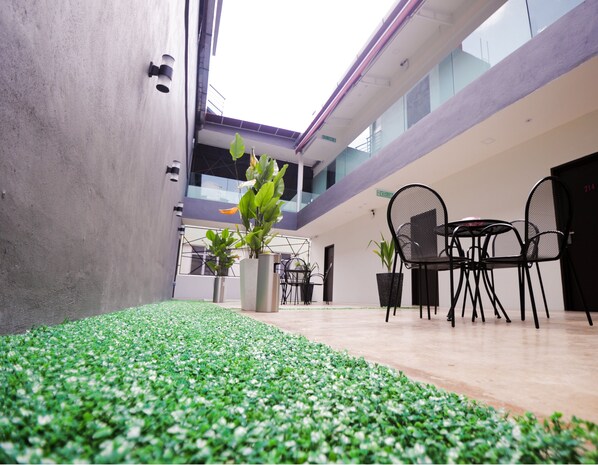 Un espace intérieur moderne avec un mur en béton, des plantes en pot et un coin salon comprenant des chaises et une table.