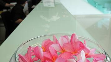 Uma área de recepção com uma mesa de vidro exibindo flores cor-de-rosa.