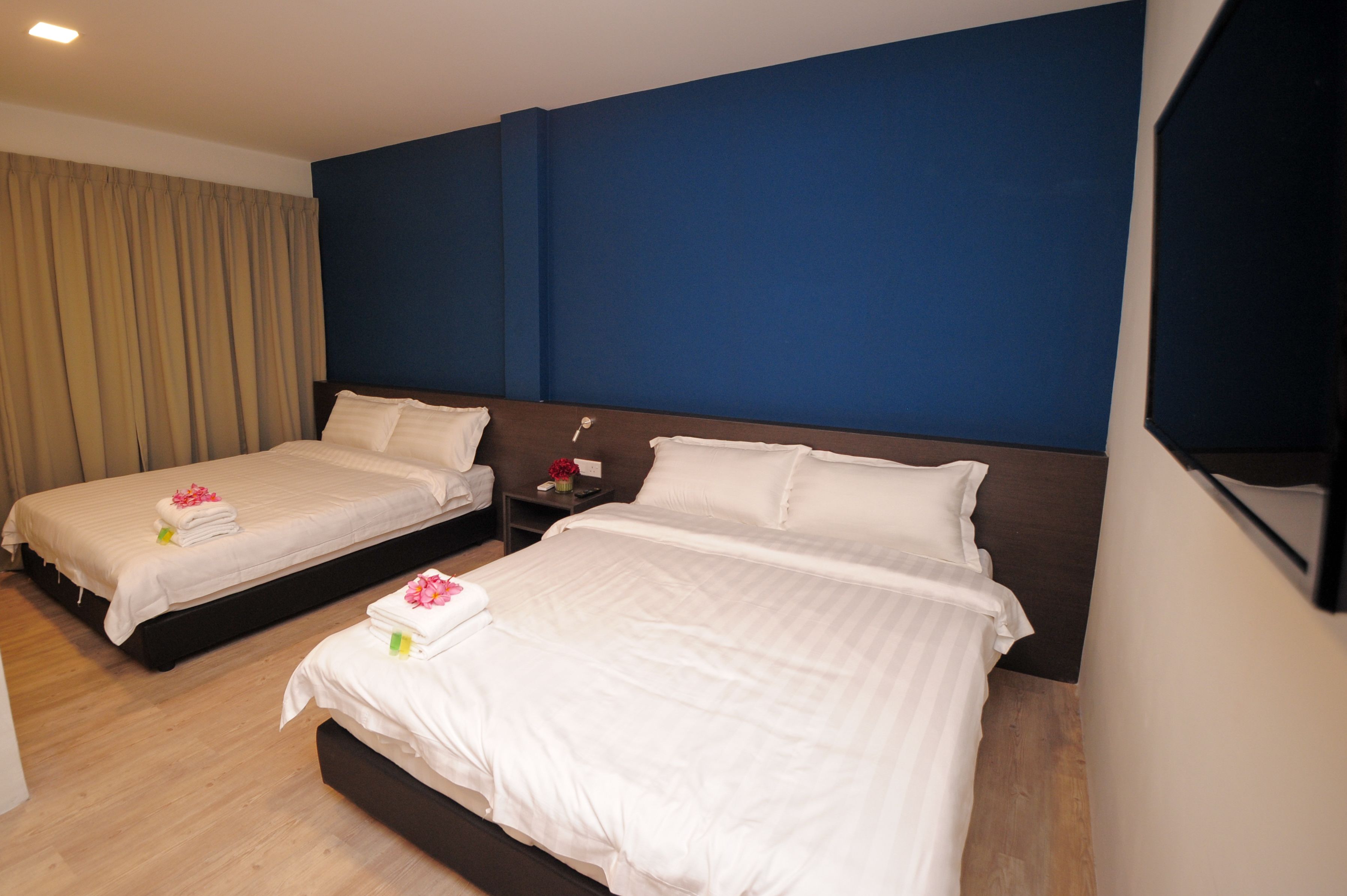 A hotel room with two beds, a dark blue headboard, and a wooden floor.