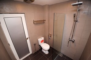 Une salle de bain équipée de toilettes, d’une douche à parois de verre et d’un porte-serviettes.