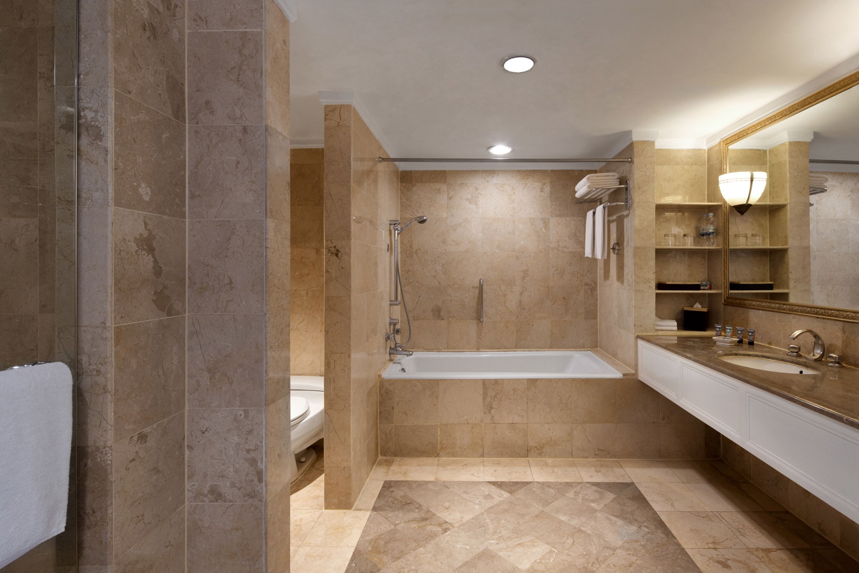 A modern bathroom with a bathtub, a large mirror, and a vanity with a sink.