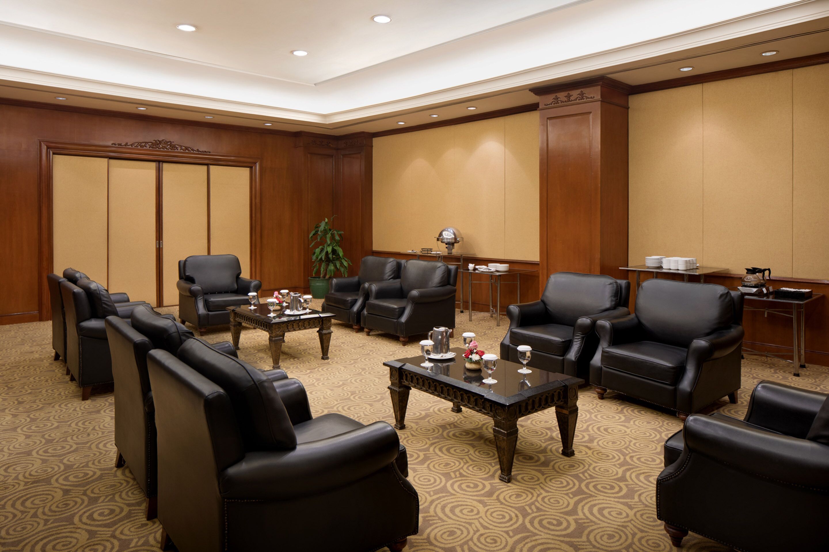 A conference room with leather chairs, a coffee table, and a projector screen.