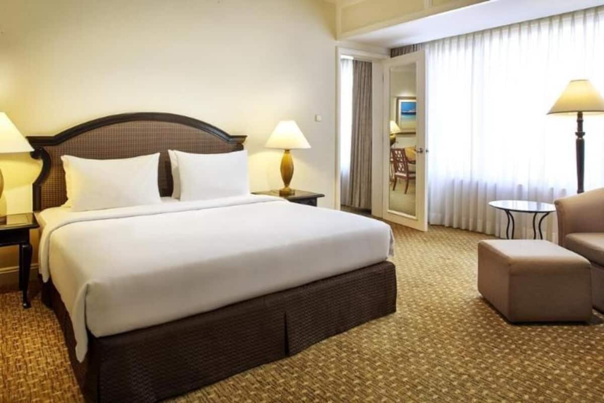 A hotel room with a large bed, two bedside tables with lamps, a chair, and a small table.