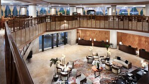 A spacious lobby with a high ceiling, multiple seating areas, and a view of the city through large windows. - Aryaduta Bandung (Bandung)